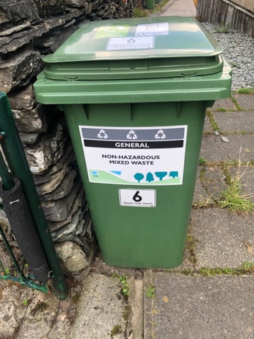 The green mixed-waste bin next to the back gate